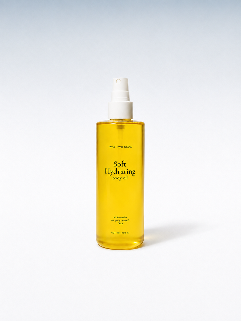 A clear plastic spray bottle filled with golden yellow body oil, featuring a white pump dispenser. The label reads 'Soft Hydrating Body oil' and 'Maya Tree Skin'.